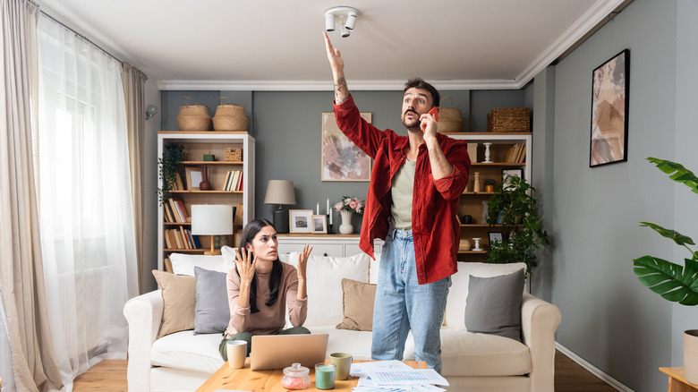 man complaining over the phone with a woman sitting beside him in a living room