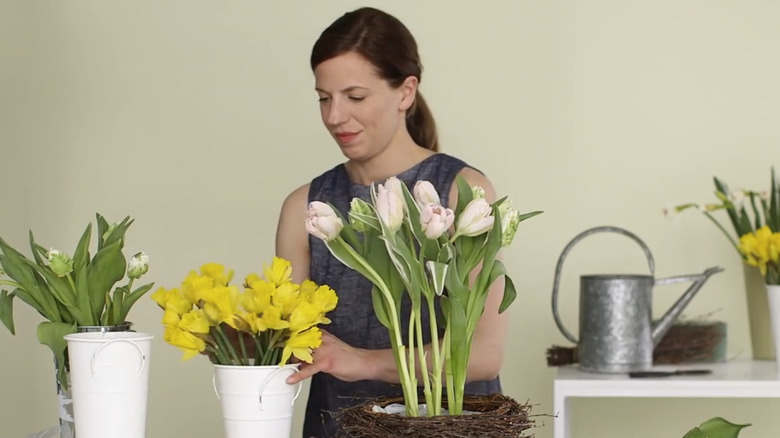 woman arranges flowers in a basket