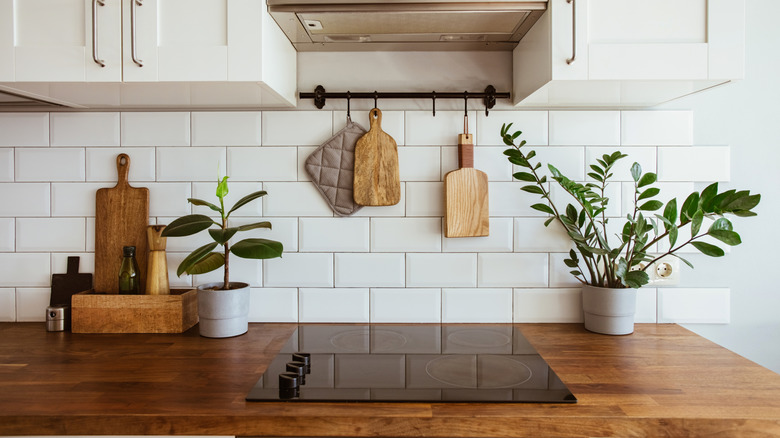 Glass cooktop in a white tiled kitchen with wood countertops and wood accents