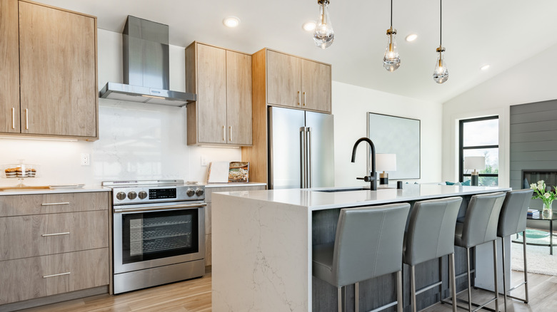 Clean, white and gray kitchen with wood flooring and cabinets.