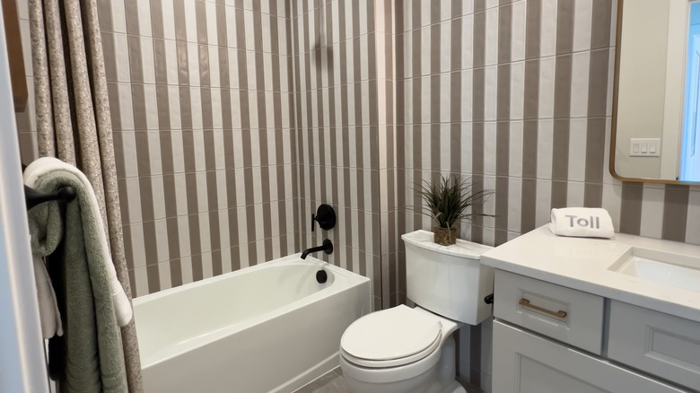 A bathroom with taupe and white striped tiles on walls