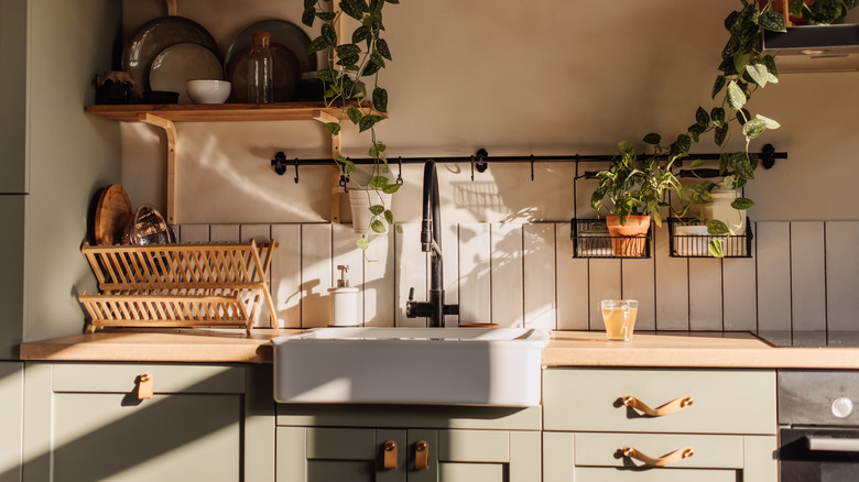 Cozy kitchen with wood countertop, white sink and grey green cabinets