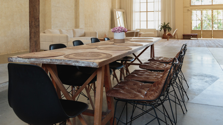 A dining table with chairs surrounding it, including brown leather Eames chairs with wire legs