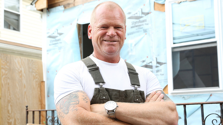 Mike Holmes stands in front of a construction site
