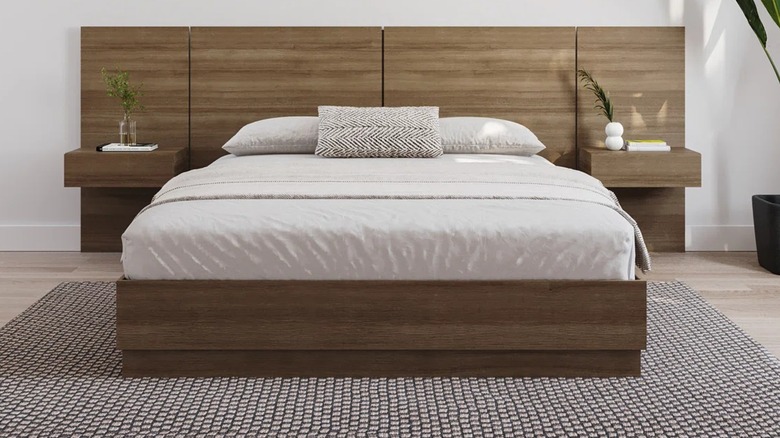 An oak-stained wood bed frame with attached side tables.