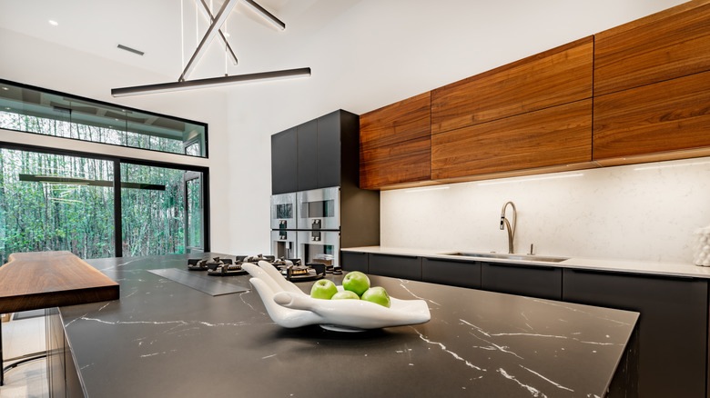 A contemporary kitchen features mismatched countertops in wood, black marble, and white stone
