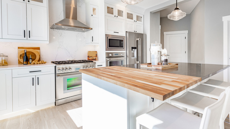 A white kitchen with a butchers block island and granite countertops