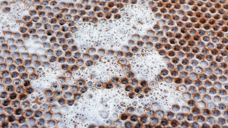 A closeup of a brown honeycomb-patterned rubber mat with soapy water on it
