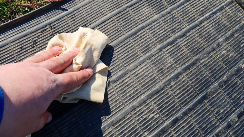 person cleaning dirty rubber mat