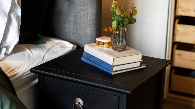 Black bedside table with books and vase