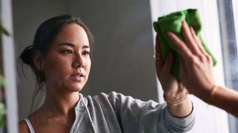 Person wiping a mirror with cloth