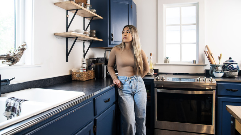 Woman leaning up against blue cabinets