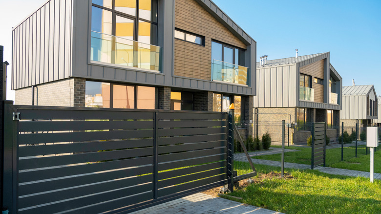 Modern two-story house with a dark horizontal slatted metal front gate