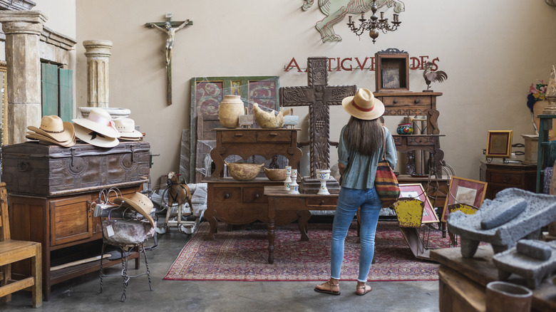 A woman stares at display of vintage furniture and decor at a second-hand store.