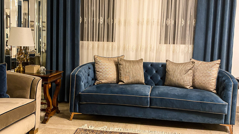 Luxurious living room featuring a blue velvet couch, which has light, warm wood tones as its foundation.