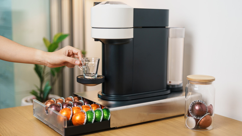 Person making coffee with a coffee pod organizer under the machine