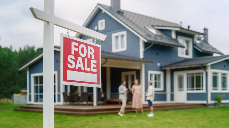 A blue home with a for sale sign