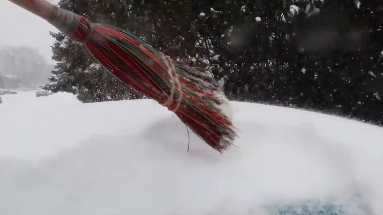 straw broom used to remove snow from car