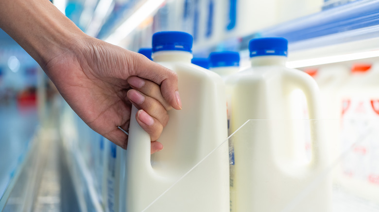 Hand grabbing a half gallon of milk from a grocery store