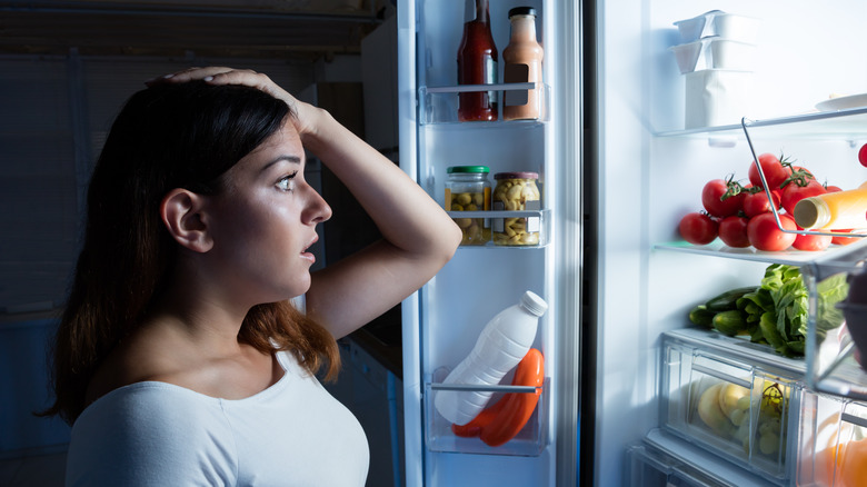 worried woman looking in refrigerator
