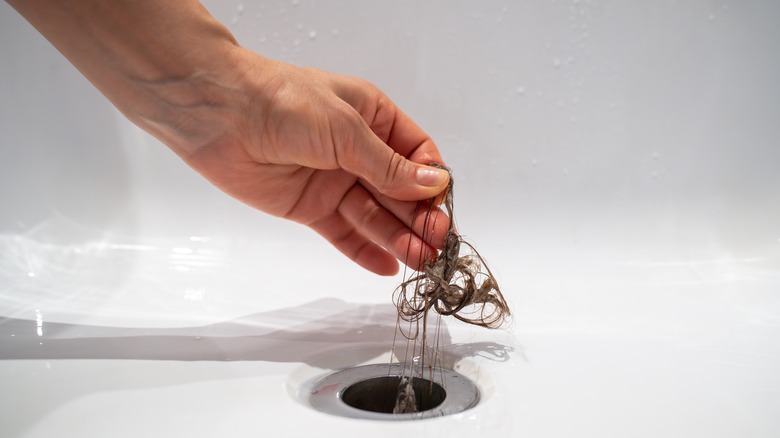 A person pulling hair out of a bathroom sink