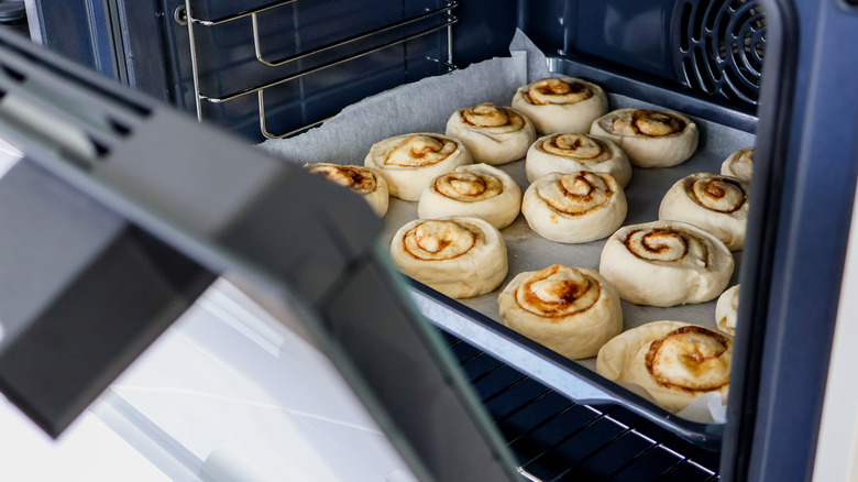 An open oven with rolls on a baking sheet inside