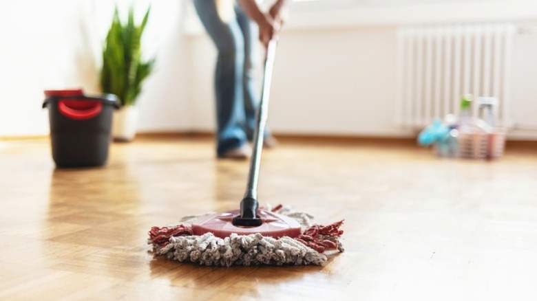 Woman mopping parquet floor with spin mop