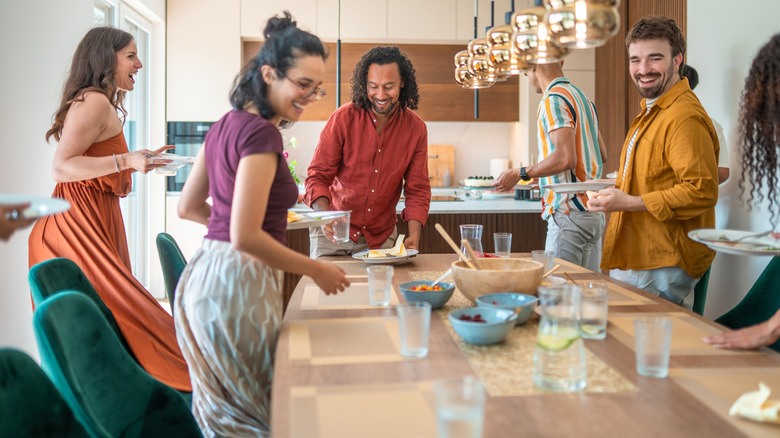 A group of people carrying their plates from the table after a meal