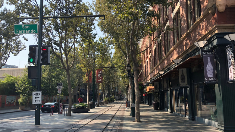 City street with trees and trolly line lines with buildings.