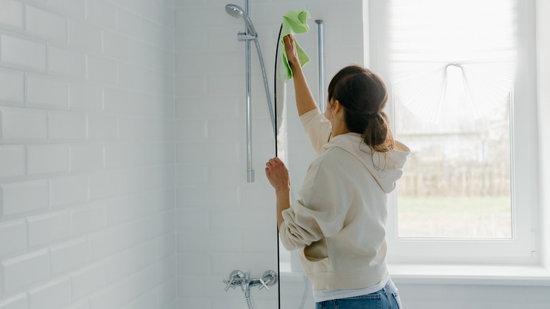 Woman cleaning shower door