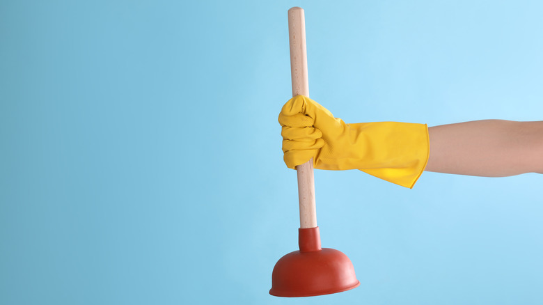 Hand holding plunger with glove