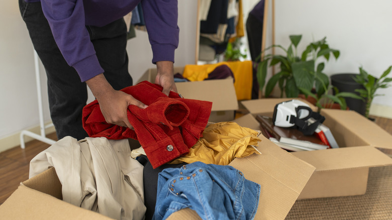 person sorting and organizing clothes in cardboard boxes at home