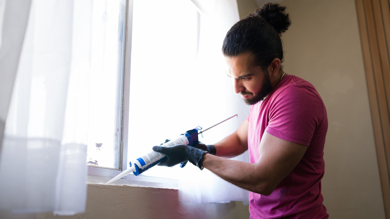 A person applying sealant around windows