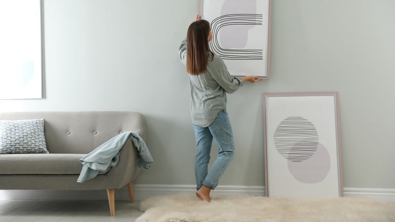 woman hanging artwork on wall