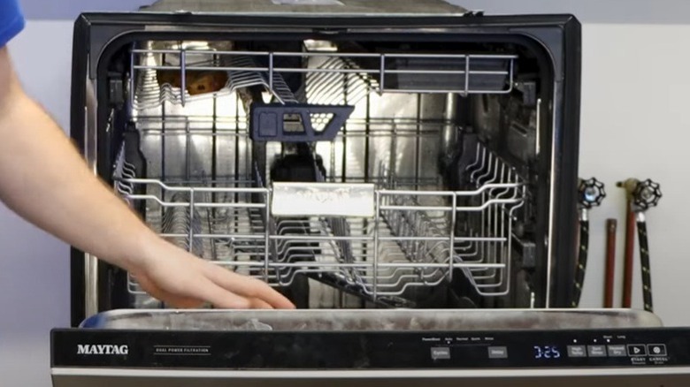 A person showing the inside of a Maytag dishwasher