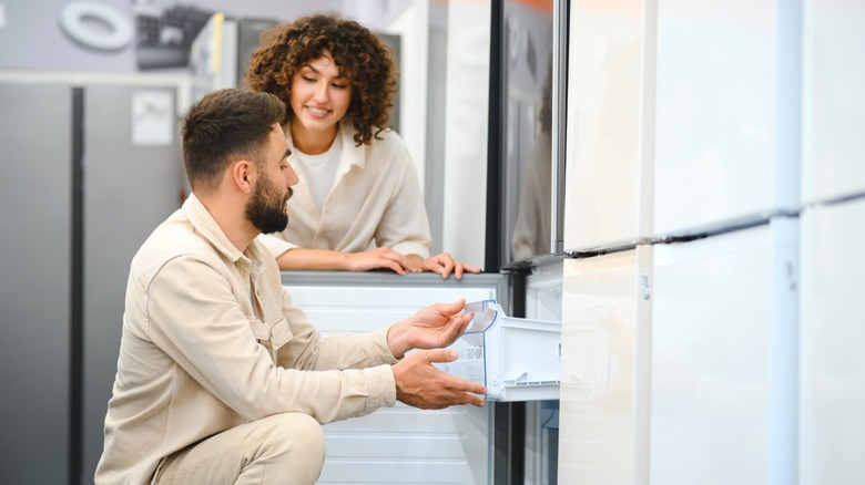 Couple looking at refrigerators on appliance store showroom