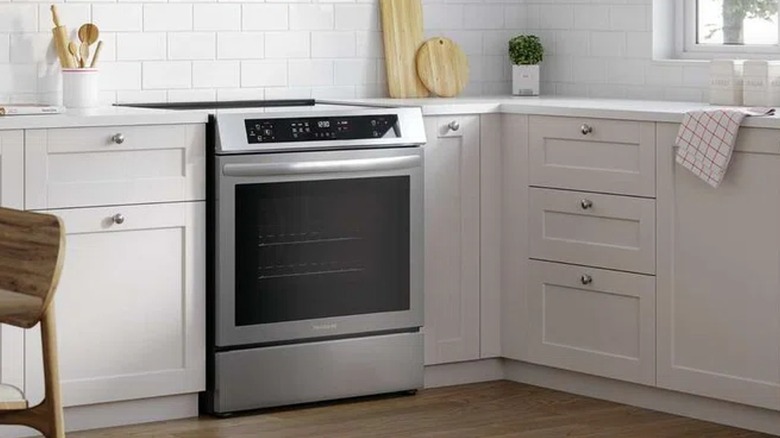 Frigidaire 30" Electric Induction Range with Convection Bake in Stainless Steel in a kitchen with white cabinets and white subway tile wall.