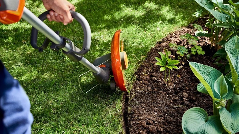 Person edging a flower bed with a Husqvarna string trimmer