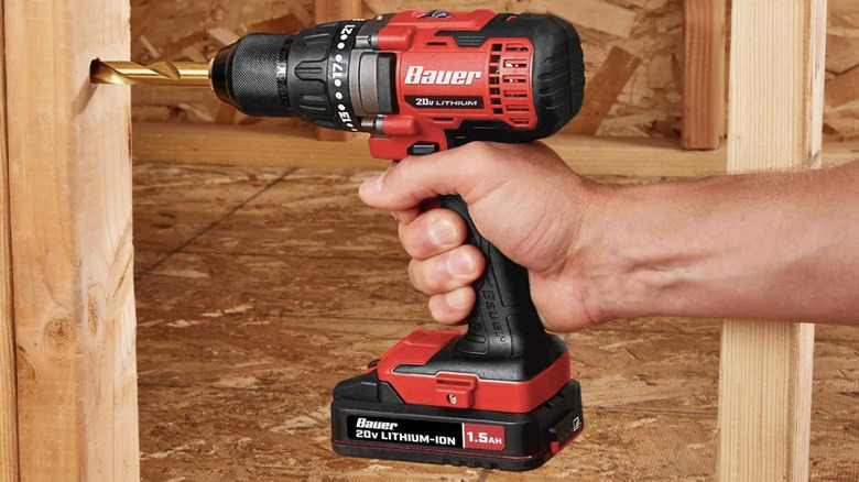 A person using a BAUER drill/driver to drill into wood