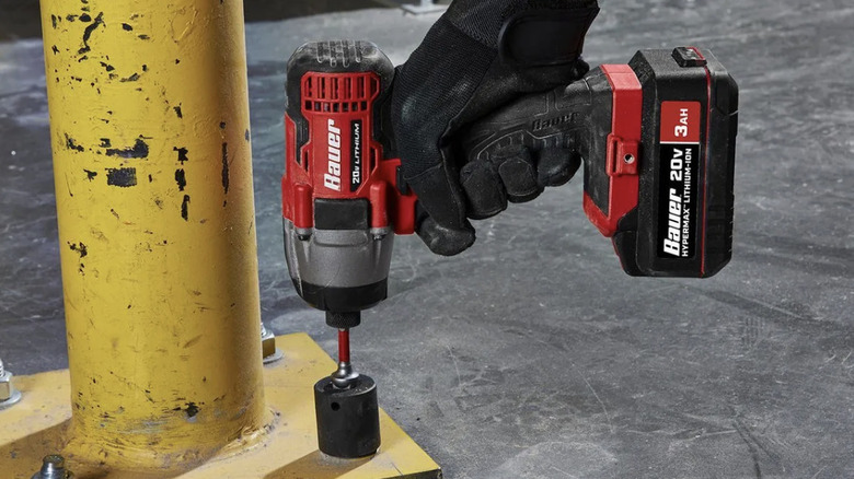 A person using an impact driver on a bolt