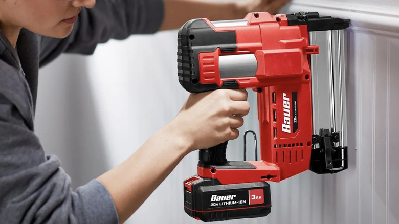 A person using a brad nailer to install wainscoting