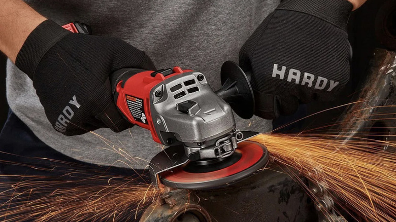 A red Bauer angle grinder being used by a man wearing gloves