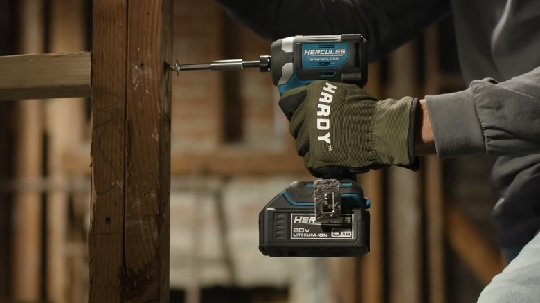 A person using a blue Hercules brand impact driver