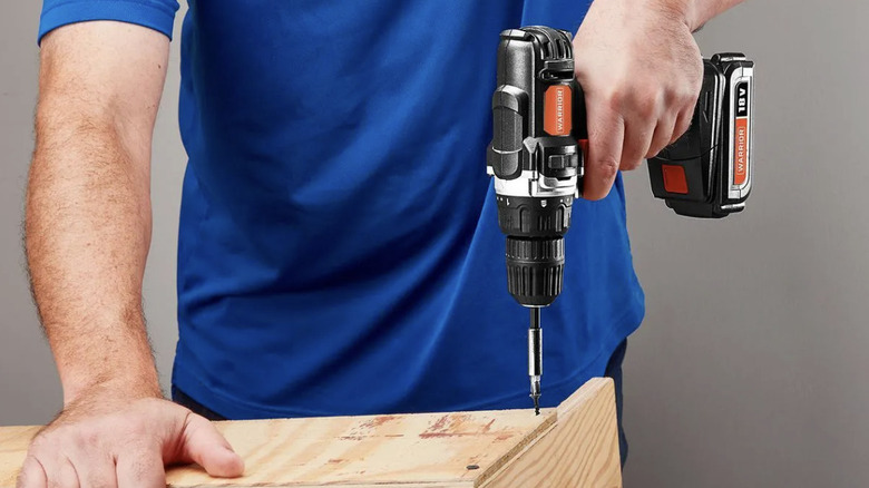 A person using a WARRIOR brand drill to build furniture