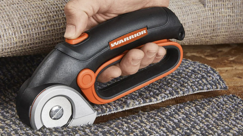 A person using a power cutter on carpet