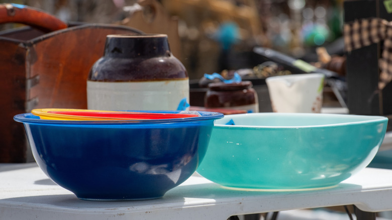 Various colors of stacked vintage Pyrex bowls at an indoor market.