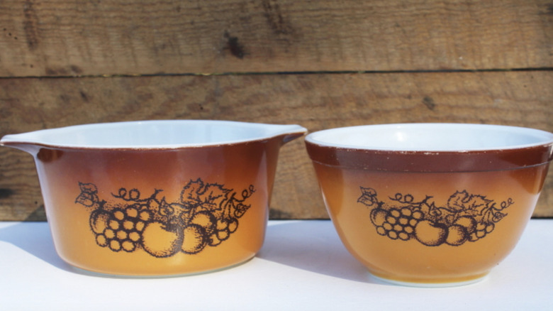 Two Old Orchard Pyrex mixing bowls with brown gradient shading and a fruit design.