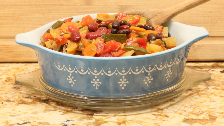 A blue and white 'Snowflake Blue' Pyrex casserole dish filled with a vegetable stew.