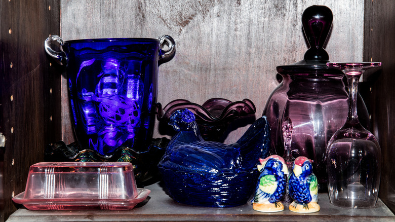 Colorful Depression glassware in cobalt blue and amethyst is on display in a china cabinet.