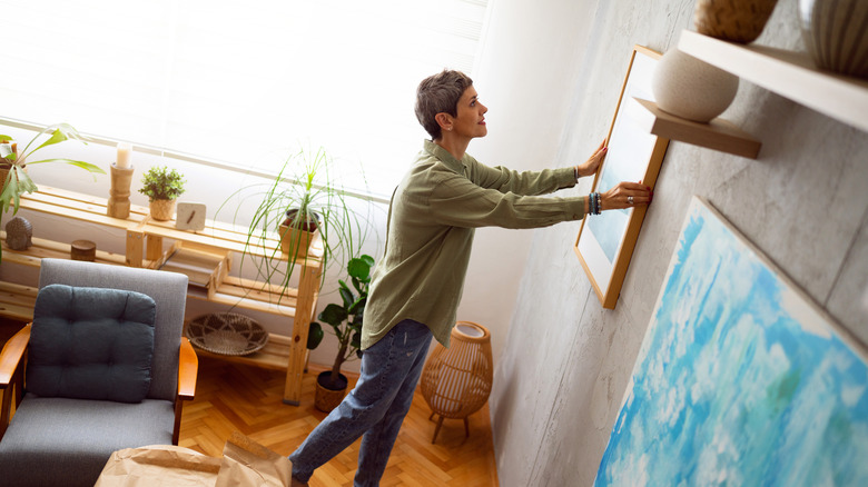 Woman hanging up framed art